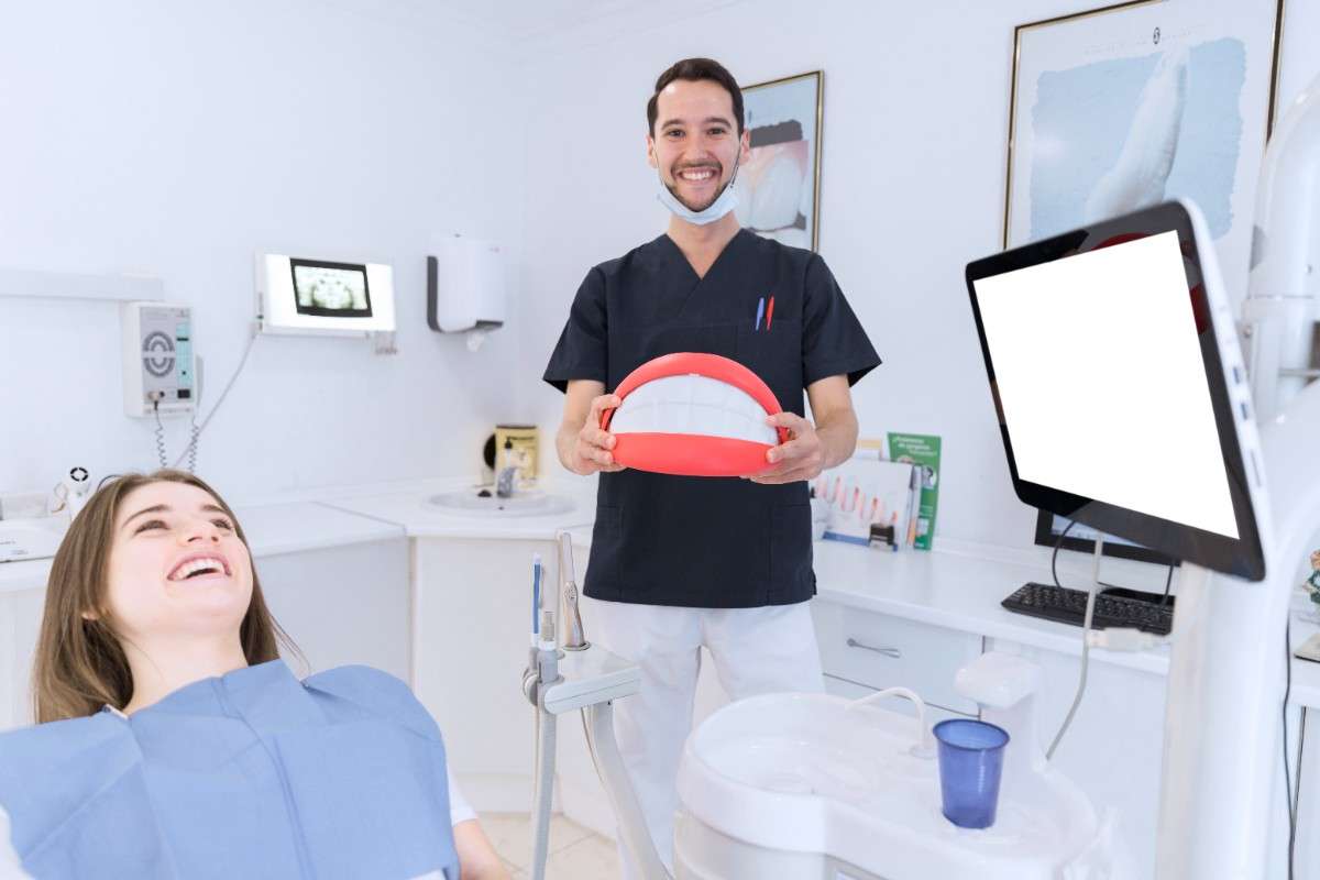 Dentist showing a dental model to a smiling patient during a dental consultation in a modern clinic